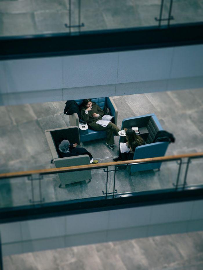 pexels-photo-35545649 Aerial view of three adults discussing ideas in a modern office lounge setting.